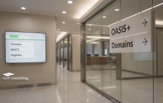 GDIC-branded office corridor with OASIS+ Domains signage and screen showing Domains, NAICS, and Eligibility.