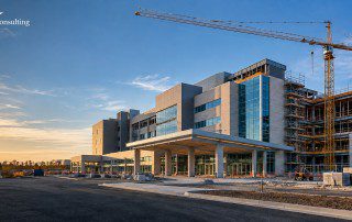 Modern healthcare facility under construction with tower crane, illustrating the VA $7.5 billion Healthcare Construction MATOC, featuring the GDIC Consulting logo.